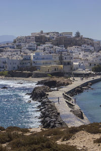 Buildings by sea against clear sky