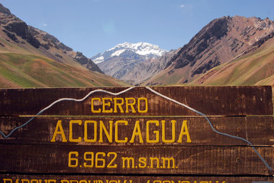 Text on road by mountains against sky