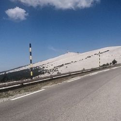 Road leading towards mountain against blue sky