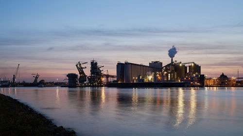 View of harbor and city at waterfront during sunset against sky