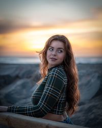 Portrait of young woman at beach during sunset