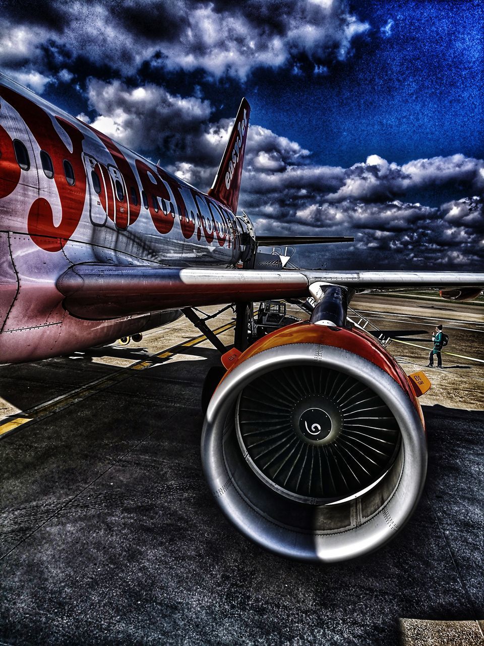 CLOSE-UP OF AIRPLANE AT AIRPORT RUNWAY AGAINST SKY