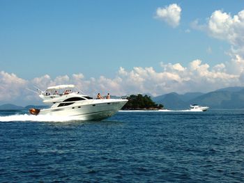 Boats in sea against cloudy sky