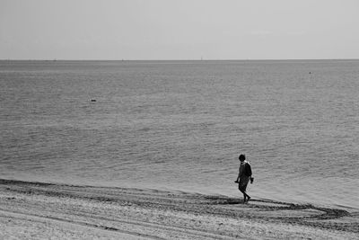 Man walking on beach against clear sky