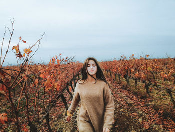 Young woman standing against sky