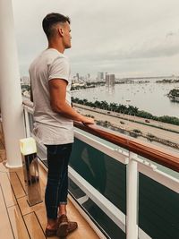 Side view of young man looking at sea while standing in balcony