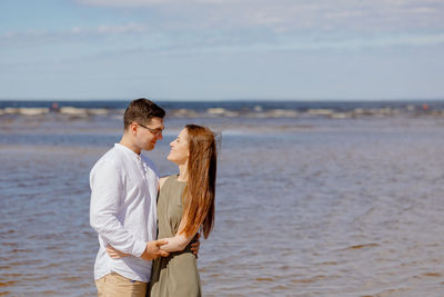 A man and a woman in love embrace portrait of young woman standing at beach