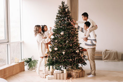 An asian multi-racial family with two children celebrate the christmas holiday in a decorated indoor