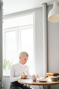 Woman sitting by coffee cup on table