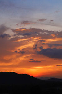 Scenic view of dramatic sky over silhouette landscape during sunset