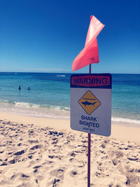 Information sign on beach against sky