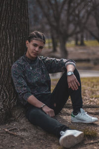 Portrait of girl sitting against tree trunk