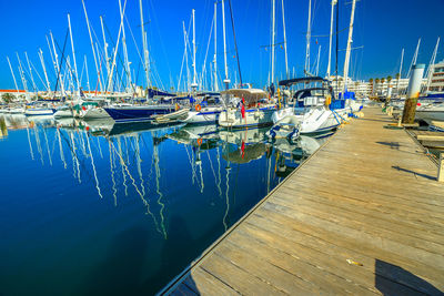 Sailboats moored at harbor against clear blue sky