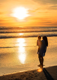 Silhouette woman walking at beach during sunset