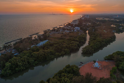 High angle view of buildings by sea against sky during sunset