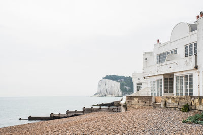 Buildings by sea against clear sky