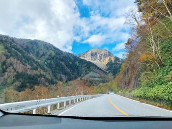 Road by mountains against sky