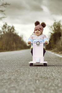 A 1 year old baby girl is with a pink motorcycle outside