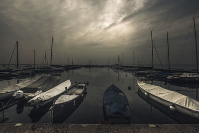 Boats moored at harbor against sky