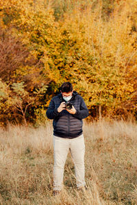 Full length of young man photographer standing in forest and shooting a photo session