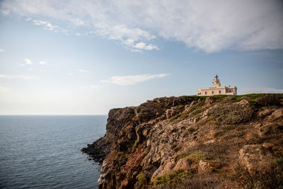 Lighthouse by sea against sky