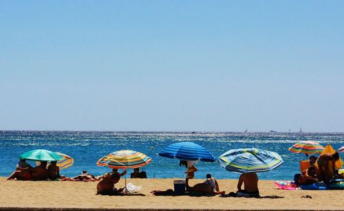 People on beach against clear sky