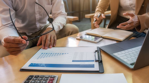 Midsection of man using mobile phone on table