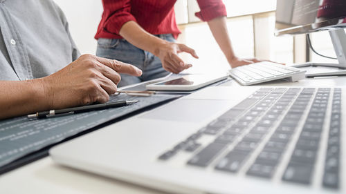 Low section of people using laptop on table