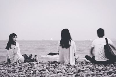 Rear view of woman sitting on rocks at beach