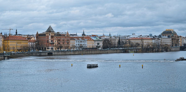 Sailboats by buildings in city against sky