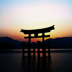 Silhouette torii gate against sky during sunset