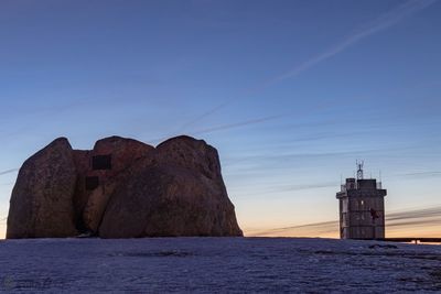 Rock formations by sea against sky during sunset