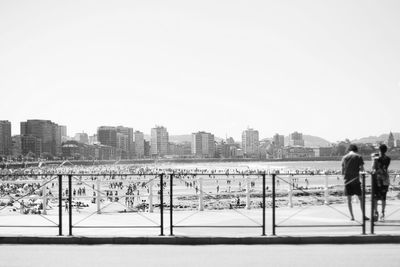 Rear view of man with snow in city against clear sky