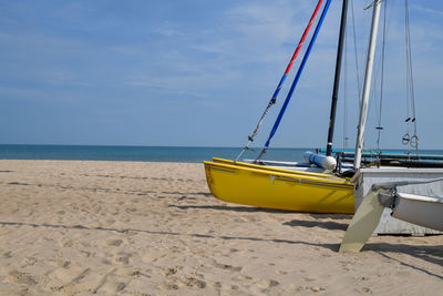 Sailboats moored on beach against sky