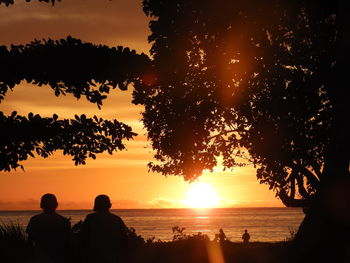 Silhouette people looking at sea against sky during sunset