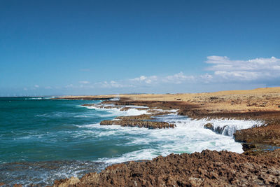 Scenic view of beach against blue sky