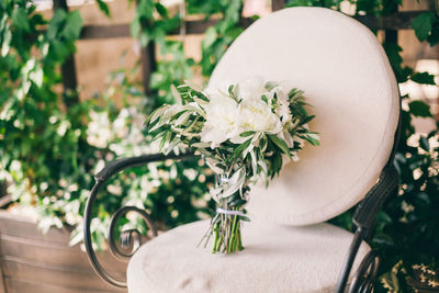 Close-up of flower vase on chair