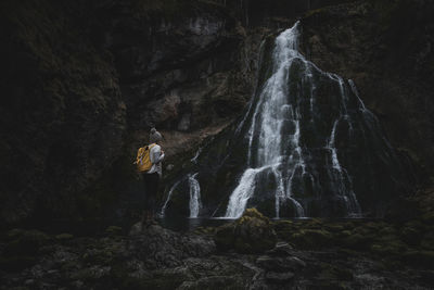 Woman on rock looking at waterfall