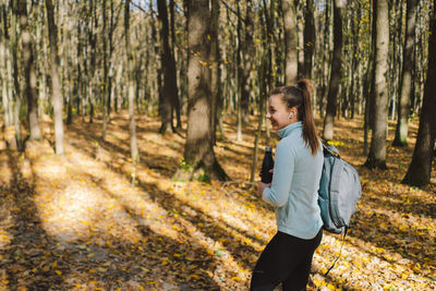 The girl drinks water. a beautiful girl is doing fitness outdoors in a sunny autumn forest