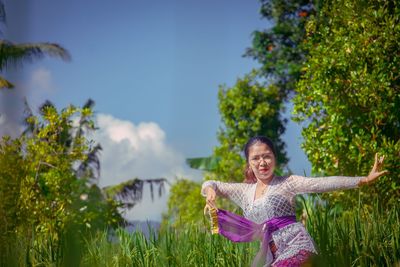 Woman standing by plants against trees