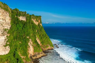 Scenic view of cliff by sea against sky at uluwatu