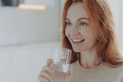 Smiling woman drinking water while looking away