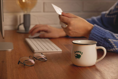 The woman makes online purchases at home on a computer.