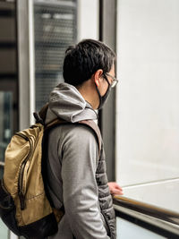 Rear view of man standing against window