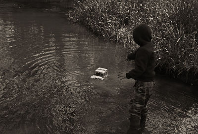 Rear view of boy standing in lake