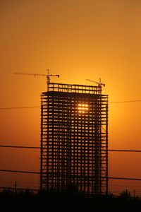 Low angle view of silhouette crane against sky during sunset