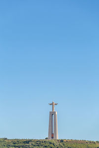 Windmill on field against clear blue sky