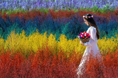 Beautiful woman walking in multi colored flowering field