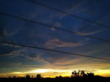 Silhouette of power lines against cloudy sky