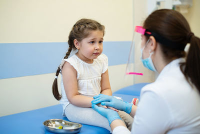 Female doctor consoling girl in hospital